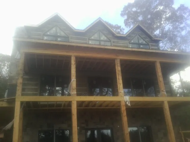 Dormers and porch framing on a large log home under construction — Roof Coating work by our crew in Clearfield
